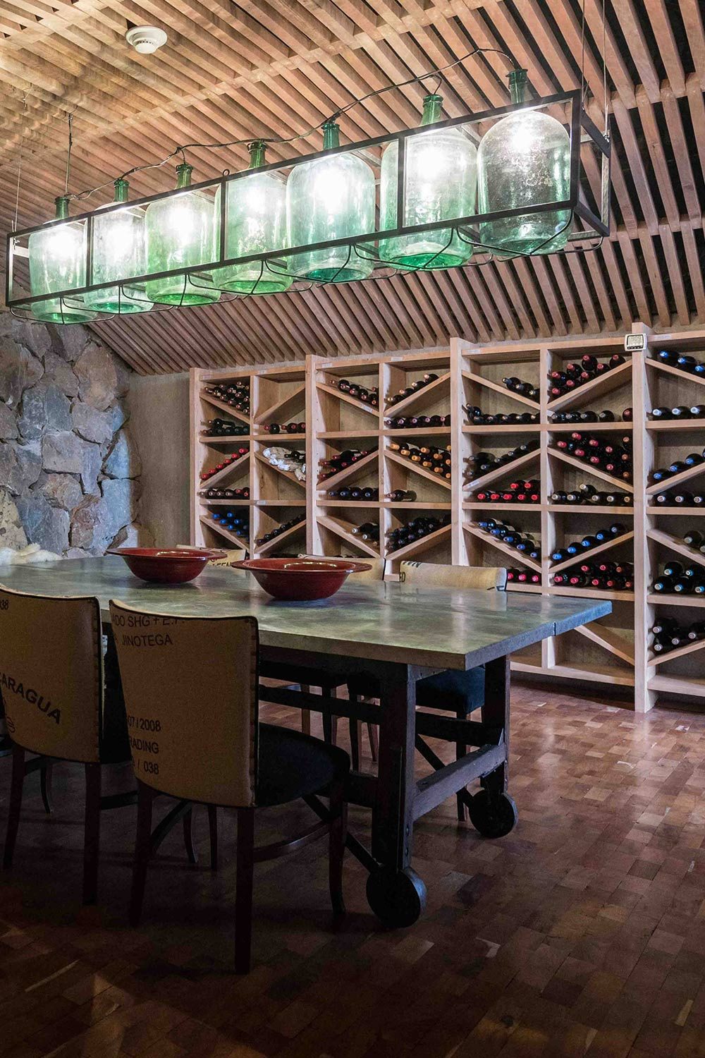 The lodge's wine cellar: wooden racks, tasting table and a chandelier made of glass demijohns