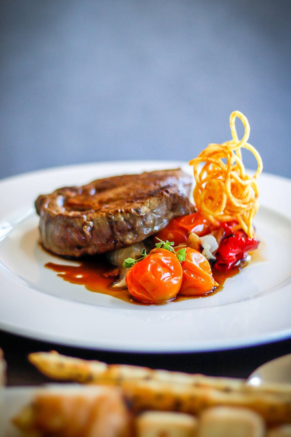 Beef tenderloin with confit tomatoes, shoestring potatoes and reduction