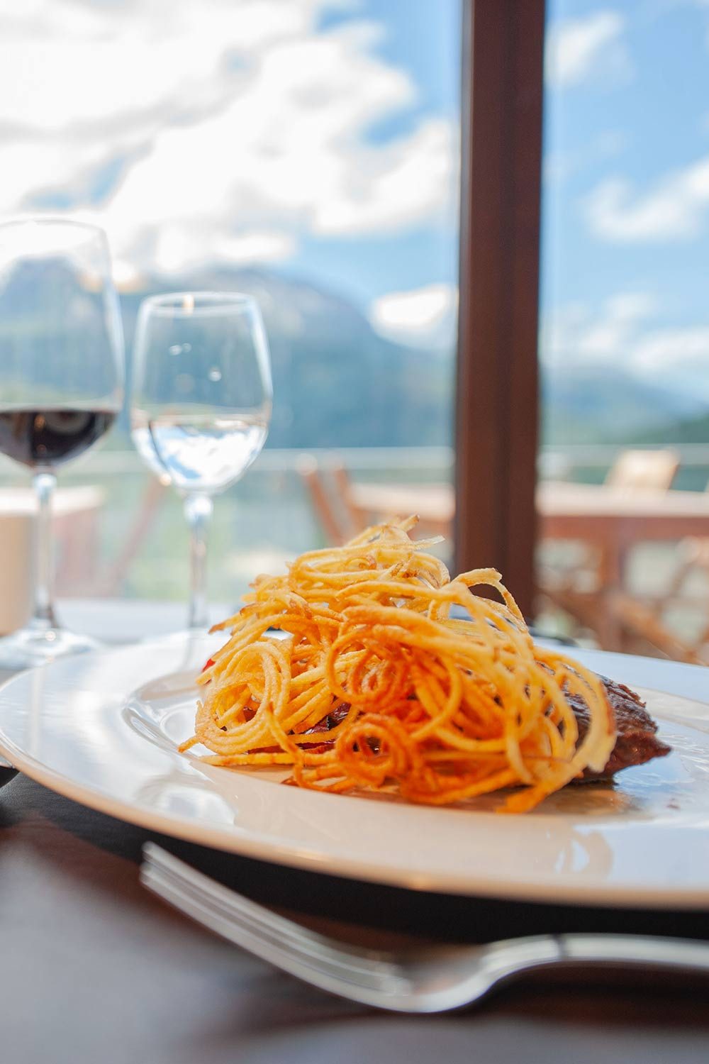 Dish served by the window with mountain views and glasses of wine