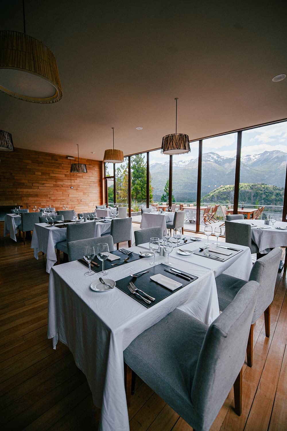 Restaurant dining room with dressed tables and a window onto the snow-capped Andes