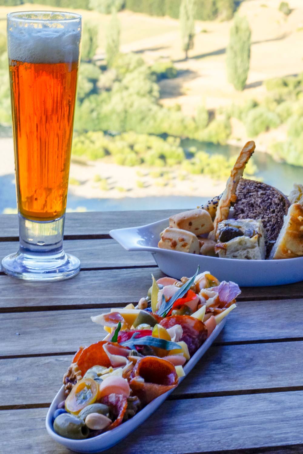 Charcuterie board with cheeses and breads on the terrace above the river