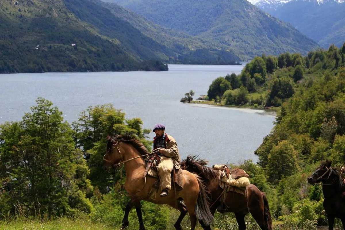 Jinete con dos caballos en un mirador sobre un lago rodeado de montañas, cerca de Futaleufú