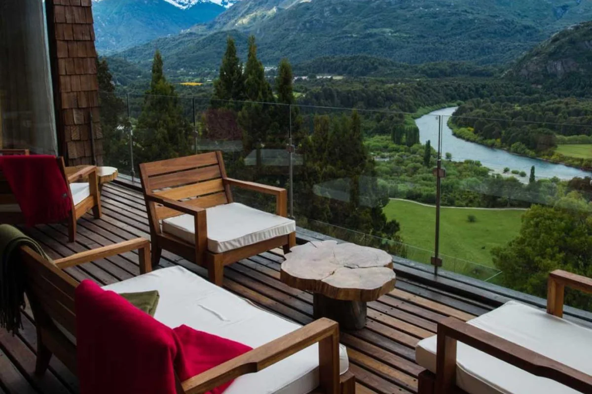 Terraza de Uman Lodge con sillones de madera frente al valle y el río Futaleufú