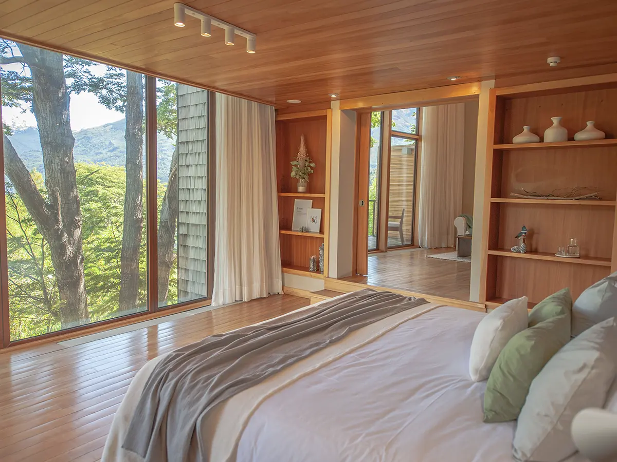 Master Suite — dormitorio con vista al bosque y estanterías de madera