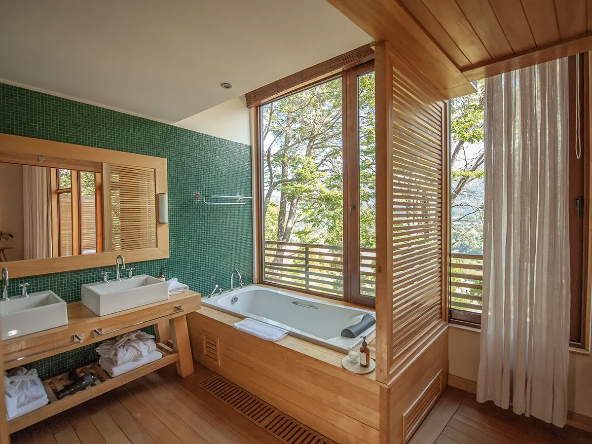 Premium Suite — baño con bañera y ventanal al bosque
