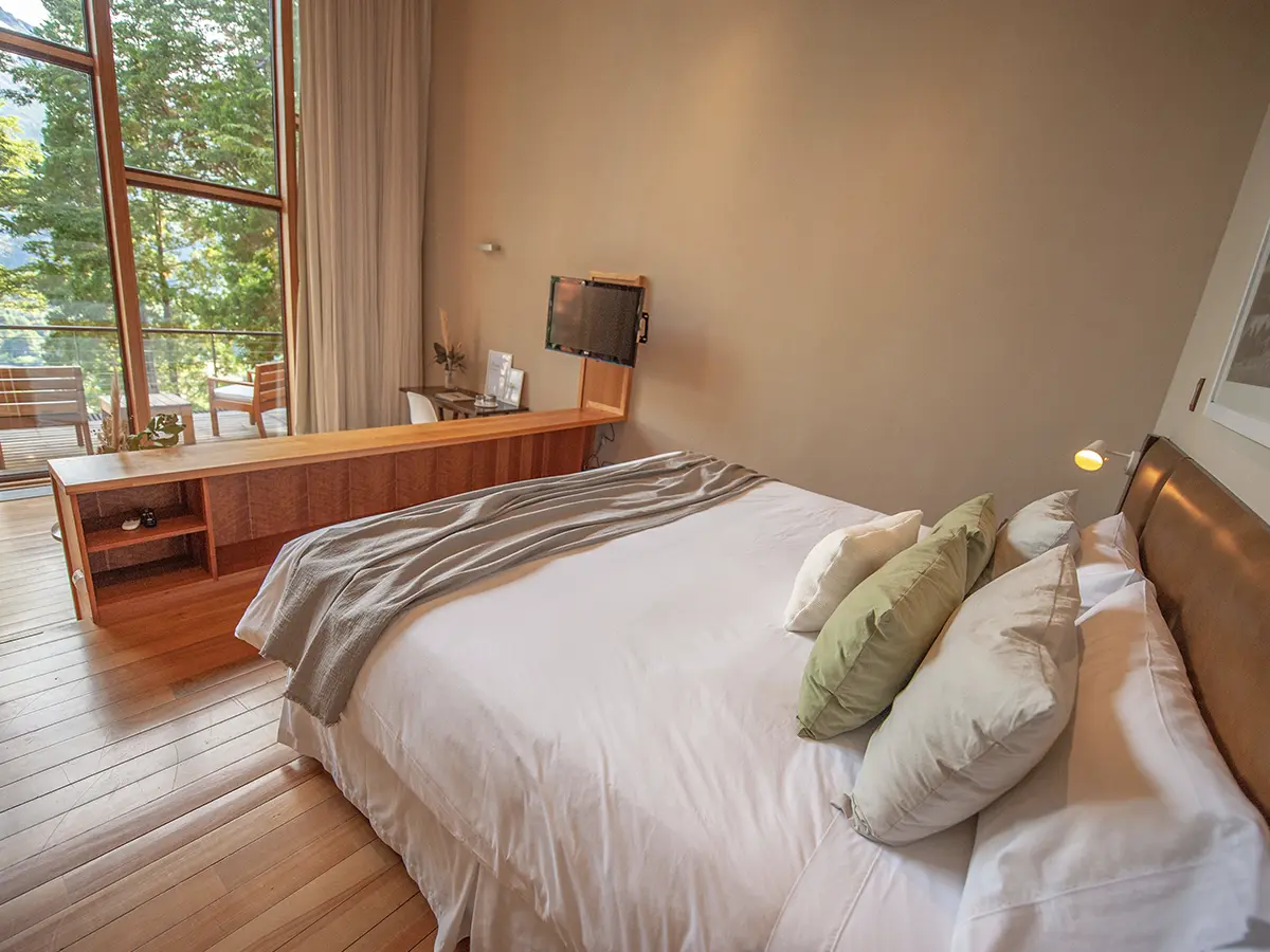 Premium Suite — dormitorio con vista al bosque desde el balcón