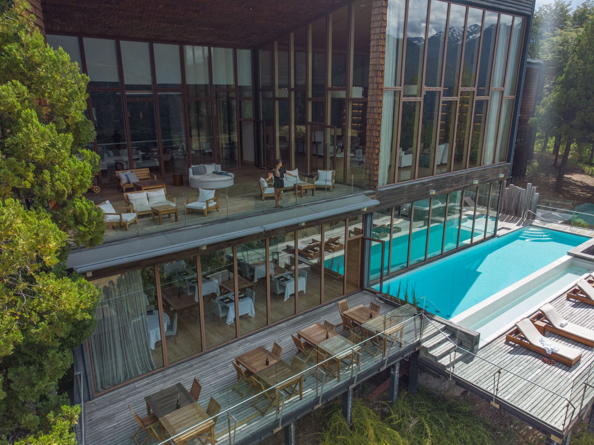 Vista aérea del lodge con piscina, terrazas de madera y la cordillera al fondo