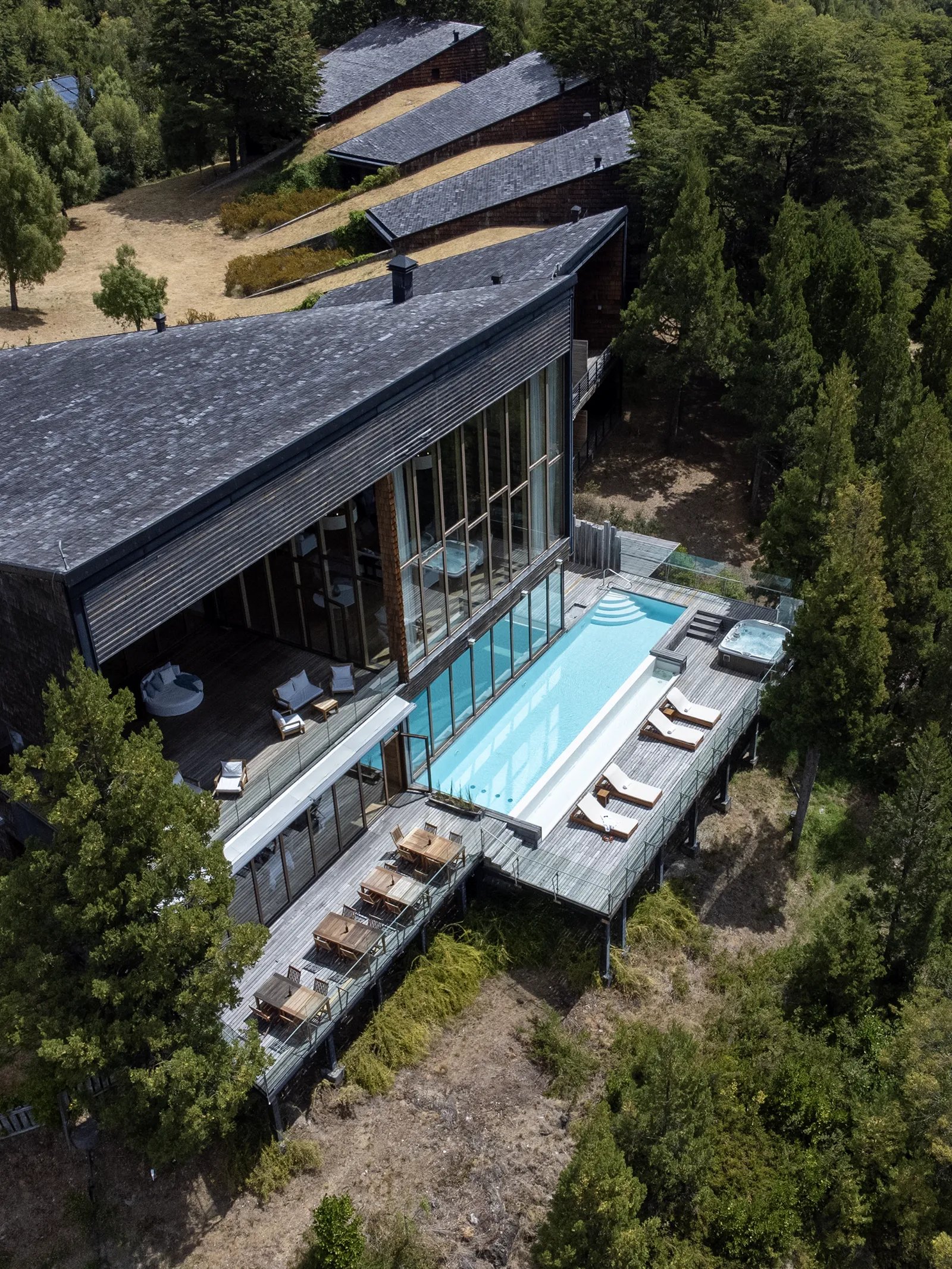Vista aérea del lodge con la piscina exterior y las habitaciones integradas al bosque