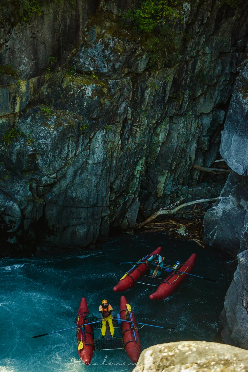 Two red safety catarafts with their guides waiting in a turquoise pool below a rock wall on the Futaleufú