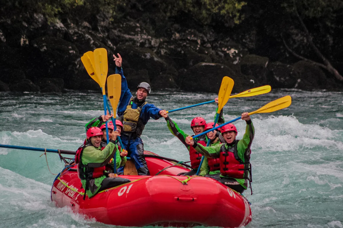 Paddlers in red helmets raising their paddles in celebration on a raft after a Futaleufú rapid